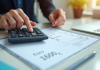 Main utilisant une calculatrice avec fiche de paie visible