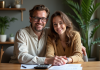 Jeune couple souriant à une table avec papiers et calculatrice